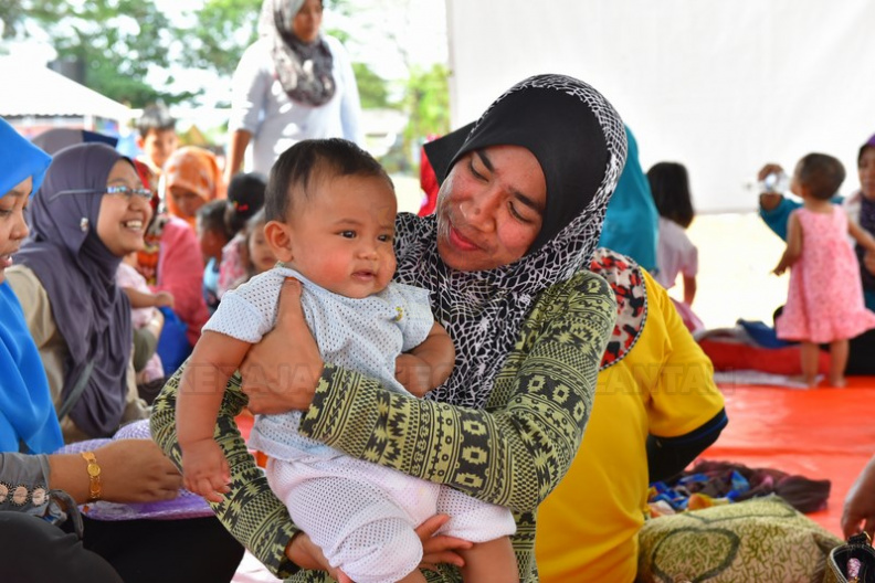 Salah seorang daripada kakitangan MAIK beramah mesra bersama penghuni pusat penempatan sementara mangsa banjir desa sakinah.JPG